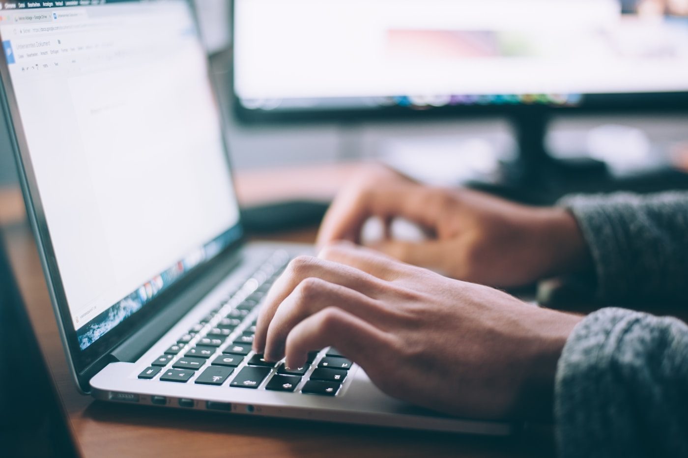 A person working from a kitchen table with a laptop in a British home